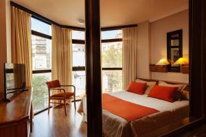 1 dormitorio con 1 cama con almohadas de color naranja y ventana en Primacy Apart Hotel en Mar del Plata