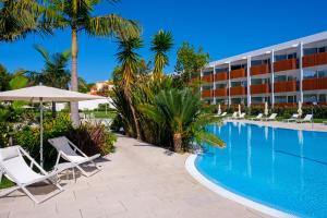 a resort with a swimming pool and chairs and a building at Malibu Foz Hotel - La Maison Younan in Figueira da Foz