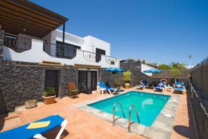 eine Villa mit einem Pool und einem Haus in der Unterkunft 4 bedroom Villa Saturn with private heated pool in Puerto del Carmen