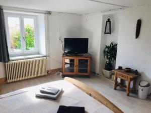 a living room with a television and a table at LE 13, Charmant appartement de 2 pièces à Lignerolle in Lignerolle