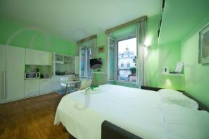 a bedroom with a large white bed and a kitchen at Ripetta 25 Prestige Rooms in Rome