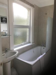 a bathroom with a tub and a sink and a window at The Weir Hotel in Walton-on-Thames