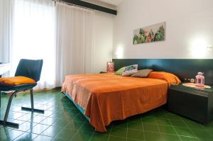 ein Schlafzimmer mit einem Bett mit einer orangefarbenen Decke und einem Stuhl in der Unterkunft Casa Vacanza Kair Trilo 263 in Sperlonga