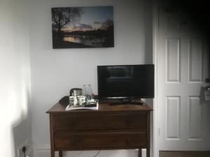 a television sitting on top of a wooden dresser at The Weir Hotel in Walton-on-Thames
