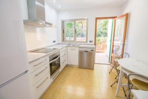 a kitchen with white cabinets and a table with a tableablish at Bonito Chalet con WiFi muy cerca del mar in Font de Sa Cala