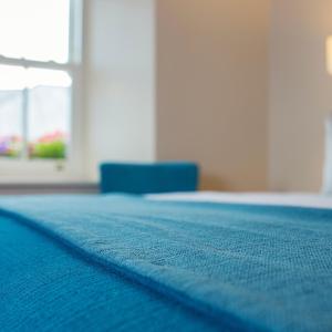 a blue blanket on a bed with a blue chair at The Wyatt Hotel in Westport