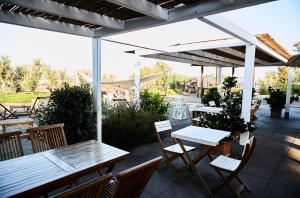 un patio con mesas y sillas bajo una sombrilla en Hotel Enterprise, en Montalto di Castro