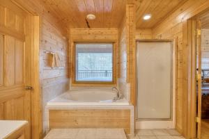 a wooden bathroom with a tub and a window at Country Living by Venture Smoky Mountains in Sevierville +22 photos