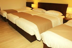 Dos camas en una habitación de hotel contigua en Rea Hotel en Heraclión