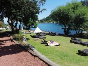 un grupo de personas yaciendo en la hierba cerca de un lago en Parque Pinares-Maravilloso-Playa -Muelle-Bosque en Pucón