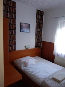 a bedroom with a bed and a window with books at Siesta Vendégház in Miskolctapolca