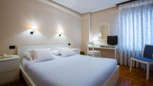 a bedroom with a large white bed with a blue chair at Hotel Casa Camila in Oviedo