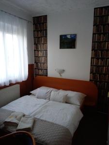 a bedroom with a bed with white sheets and a window at Siesta Vendégház in Miskolctapolca