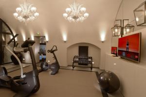 a gym with exercise equipment and a television and chandeliers at Hotel La Lanterne & Spa in Paris