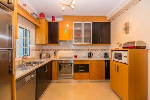 uma cozinha com armários de madeira e eletrodomésticos de aço inoxidável em Villa Engiadina by ALGARVEMANTA na Manta Rota