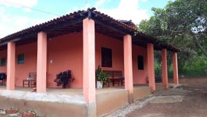 een rood huis met twee banken ervoor bij Hospedagem Flor de Araca in Ibicoara