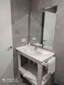 y baño con lavabo y espejo. en hostal la taurina, en Santa Olalla de Toledo