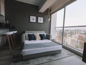 een slaapkamer met een bank en een groot raam bij Trendy Host Connect, Barranco in Lima