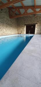 einen Pool in einem Steingebäude mit einem blauen Pool in der Unterkunft Bed and Breakfast au Champ du Douits in Saint-Agnan-le-Malherbe
