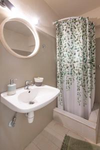 a bathroom with a sink and a shower curtain at Puerto Seaside Rooms in Akhladherí