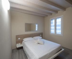 a white bedroom with a bed and a window at Locanda la torre in Calvisano