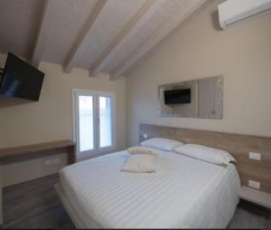 a white bedroom with a bed and a television at Locanda la torre in Calvisano