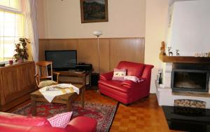 a living room with a red chair and a fireplace at Klösterle Hof in Bad Rippoldsau-Schapbach