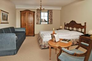a bedroom with a bed and a couch and a table at Hotel BurgGartenpalais in Rothenburg ob der Tauber +67 photos