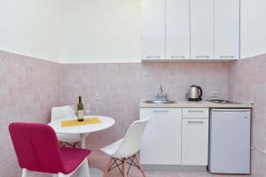 a kitchen with white cabinets and a table with a bottle of wine at Apartment Stari Grad in Budva