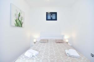 a white bedroom with a bed with two white towels at Apartment Stari Grad in Budva