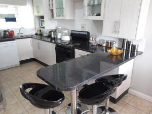 a kitchen with a black counter top and black stools at Sheilas home away from home in Lusaka