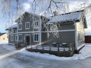 a gray house with a porch in the snow at HH&S Gåxsjö in Hammerdal