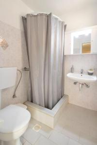 y baño con cortina de ducha, aseo y lavamanos. en Puerto Seaside Rooms, en Akhladherí