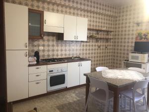 una cucina con elettrodomestici bianchi e tavolo con sedie di B & B Patrizia a Isola Capo Rizzuto