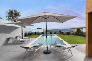 a patio with an umbrella and chairs and a pool at Amaré Chania Luxury Residence in Stérnai