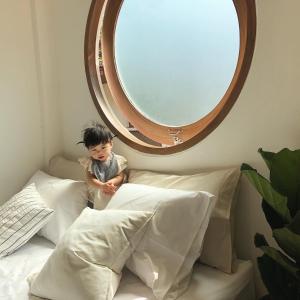 um rapazinho sentado numa cama debaixo de um espelho em Marlowe-Tony's home em Bangkok