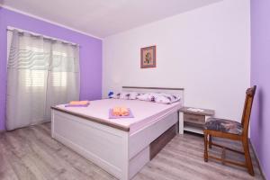 1 dormitorio con 1 cama blanca grande con silla en Apartments Makarska Gudelj Cvitan, en Makarska