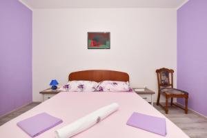 a bedroom with a bed with purple pillows and a chair at Apartments Makarska Gudelj Cvitan in Makarska