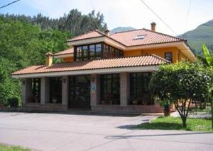 una gran casa amarilla con techo de baldosa en Hotel Benzua, en Villanueva de Ardisana
