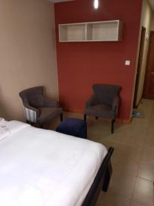 a hotel room with a bed and two chairs at Nairobi west suite in Nairobi