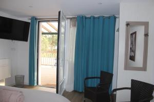 1 dormitorio con cortinas azules y puerta corredera de cristal en LES CHAMBRES DU HOURON, en Moliets-et-Maa