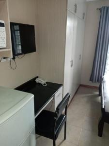 Habitación con escritorio con silla y TV. en Nairobi west suite en Nairobi