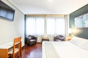 um quarto de hotel com uma cama, uma secretária e cadeiras em Zumaia Hotela em Zumaia