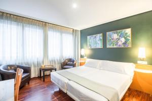 um quarto de hotel com uma cama e uma cadeira em Zumaia Hotela em Zumaia