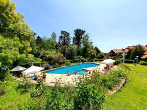 a large swimming pool with people in a yard at Hotel La Cumbrecita in La Cumbrecita