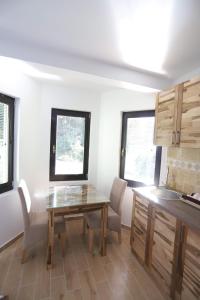 cocina con mesa de madera, sillas y ventanas en Vila PARADIZO-ZLATAR, studio apartman 1 en Nova Varoš