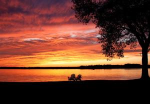 ławka siedząca obok jeziora o zachodzie słońca w obiekcie Sandaway Suites & Beach w mieście Oxford