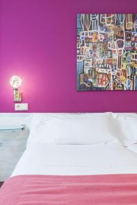een slaapkamer met een roze muur met een bed en een schilderij bij Zumaia Hotela in Zumaia