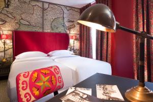 a bedroom with a bed and a table with a lamp at Hôtel du Continent in Paris