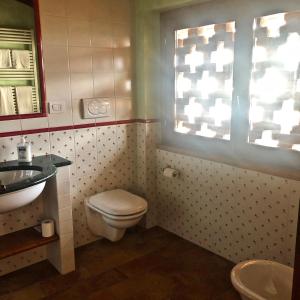a bathroom with a toilet and a sink and a window at Villa Redona in Entratico